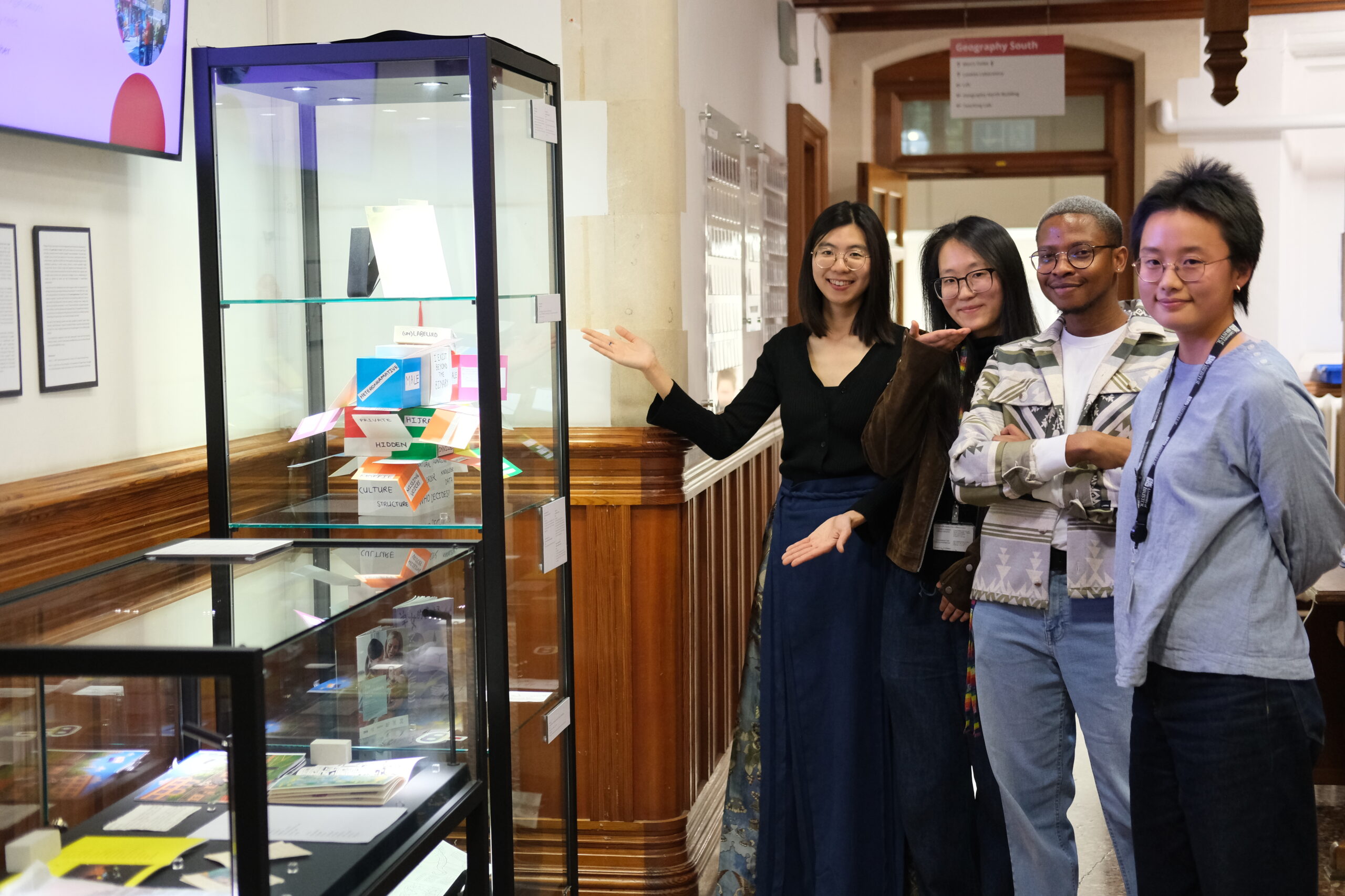 Exhibition coordinators beside cabinet showcasing objects.